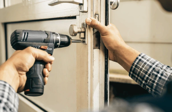 Close-up of a technician driving fixings into the lock body and strike on the edge of a commercial door